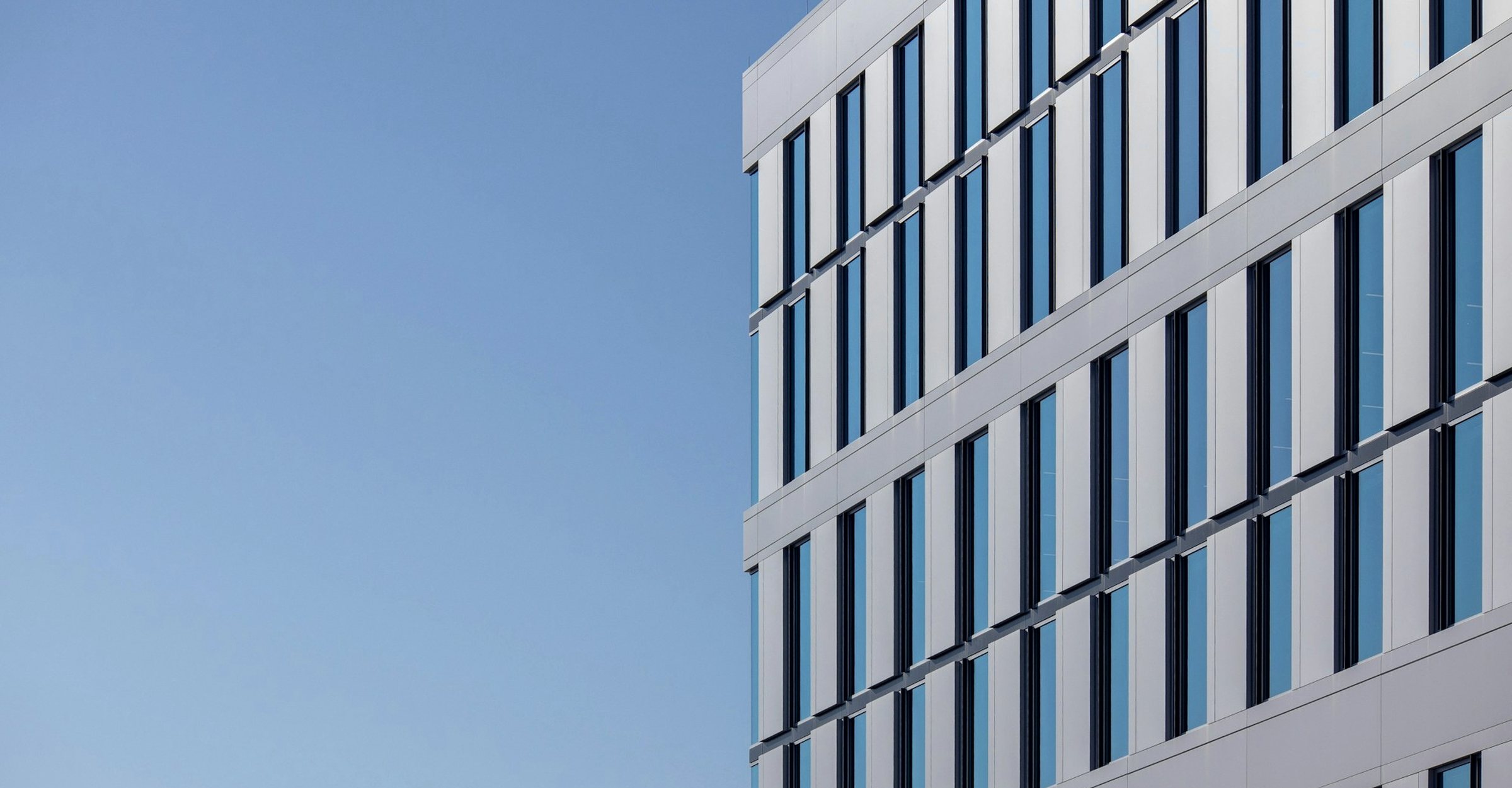 A glass and steel office facade against a clear sky
