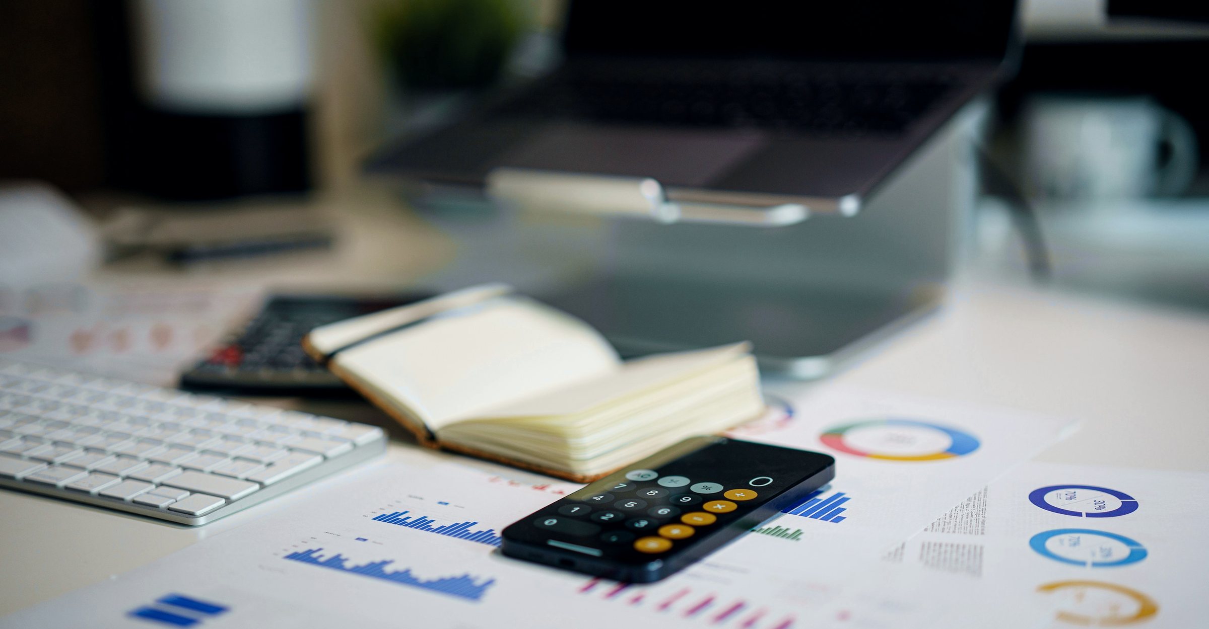 Financial charts, a calculator and a notebook on a desk